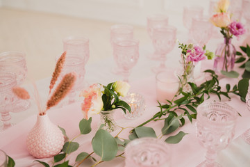 Coziness and style. Modern event design. Table setting at wedding reception. Floral compositions with beautiful flowers and greenery, candles, laying and plates on decorated table.