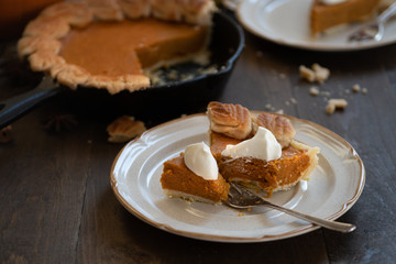 Homemade pumpkin pie baked in cast iron pan, on wooden background