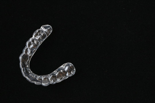 Macro close up of a plastic teethguard to stop wear due to teeth grinding at night isolated against black background.