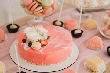Candy bar with tasty desserts and appetizers at wedding reception. Decorated with flower compositions and candles. Sweet food, dessert, buffet, catering table, restaurant.