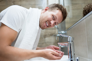 young handsome man washes his face in bathroom