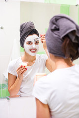 Home spa. Smiling woman applying clay mask