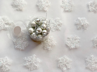 Obraz na płótnie Canvas Box with christmas silver balls across white snowflakes background. Copy space. Christmas card. Christmas concept