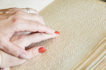 woman reading braille text on old book