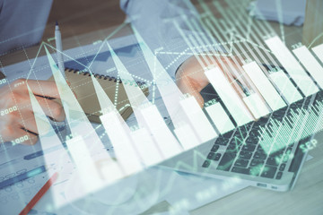 Forex graph with businessman working on computer in office on background. Concept of hardworking. Double exposure.