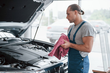 Man in blue uniform works with broken car. Making repairings