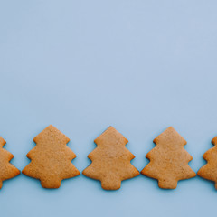 Holiday cookies in the shape of Christmas tree on light blue background. Space for text.