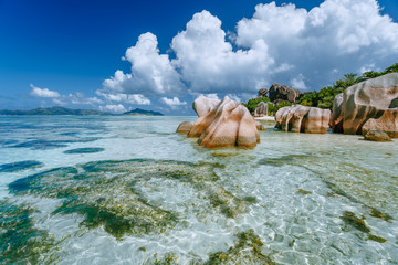 Fototapeta na wymiar Anse Source d'Argent in low tide - Paradise tropical beach with shallow blue lagoon, granite boulders and white clouds above. La Digue island, Seychelles