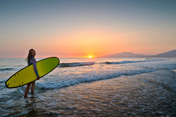 Swedish beautiful girl surfing at sunset in Los Lances Beach, Tarifa, Cadiz, Andalucia, Spain