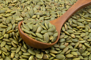 Pumpkin seeds and wooden spoon close up