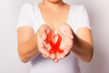 Closeup of female with red ribbon Support HIV AIDS on hands