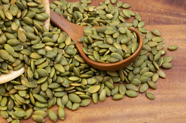 Pumpkin seeds with wooden spoon and wooden bowl