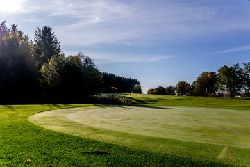 Obraz premium green grass golf course in fall with autumn leaves and trees