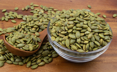 Pumpkin seeds with wooden spoon and glass bowl