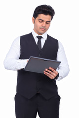 Fototapeta na wymiar Handsome young businessman using digital tablet. Male entrepreneur is preparing presentation on wireless computer. He is wearing formals on white background.