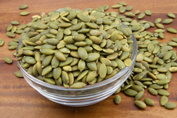 Pumpkin seeds in glass bowl on wooden table