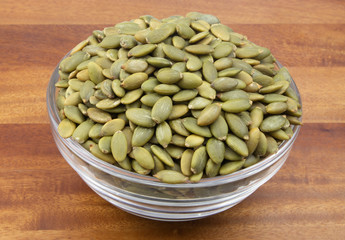 Pumpkin seeds in glass bowl on wooden table