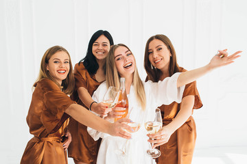 hen party. Beautiful charming women wearing in satin robe drinking alcohol and enjoying pajamas...