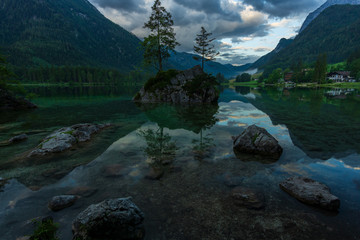 A clear mountain lake with dark clouds and high mountains in the background - 296348781