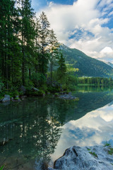 A clear mountain lake with dark clouds and high mountains in the background - 296348999