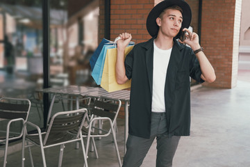 man holding shopping bags & talking on mobile smart phone.