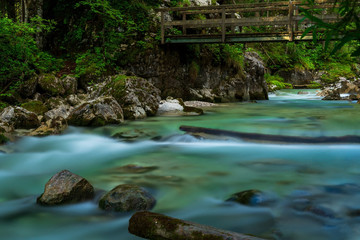 A river in the mountains with stones and green trees as a long exposure - 296349597