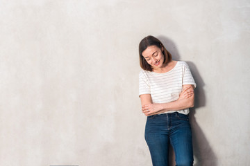 middle aged woman smiling by gray wall with arms crossed