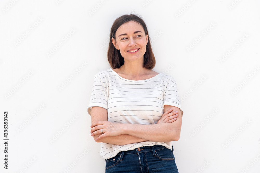 Wall mural smiling older woman standing by white background with arms crossed and glancing