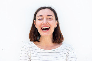 Close up attractive older woman laughing by white background