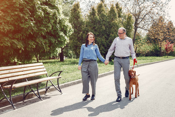 Couple in a forest. Adult pair with cute dogs. Lady in a blue shirt