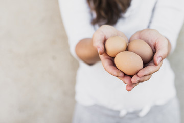 Woman in white shirt holding  brown eggs in her hands - Powered by Adobe