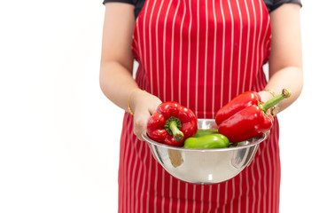 Woman hands holding fresh sweet peppers in a bowl isolated on white background.