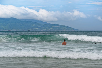 Beach scene of high waves an a single man going toward the wave, relaxed, concept of vacation on the beach