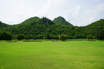 View of green park with the waterworks, white cloud and mountains 