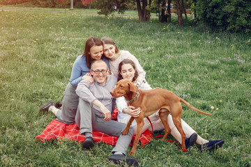 Family in a summer park. People sitting with a dog. Parents with a two daughters