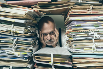 Depressed businessman overwhelmed with paperwork