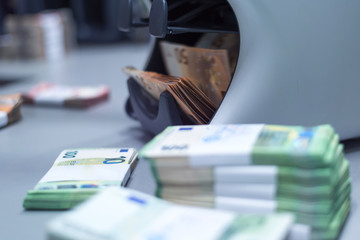 Bank employees sorting and counting money inside bank vault.