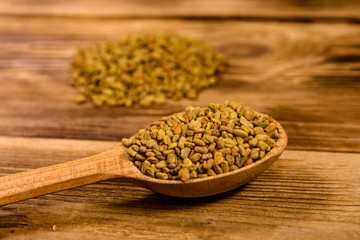 Spoon with fenugreek seeds on wooden table