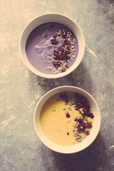 It's soup season, two bowls full of pumpkin and coconut soup one and the other violet potatoes soup, on a green and yellow  background,flat lay composition, healthy warm food for autumnal and winter s