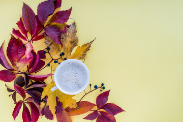 Autumn composition. mug of cappuccino and yellow and red leaves with berries on a yellow background. autumn background. flat lay, top view, copy space