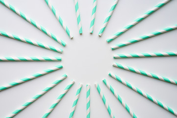 pile of paper striped white and green drinking straws located in the shape of a sun and sunbeams on a white background. space for text