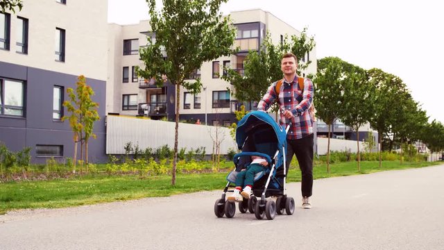 family, leisure and people concept - father with little son in stroller walking along city street