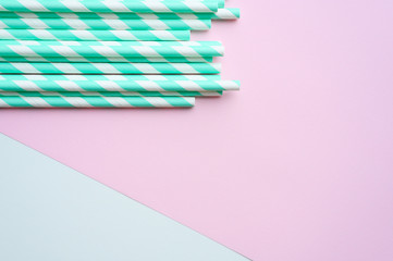 pile of paper striped white and green drinking straws for party on white and pink background. space for text