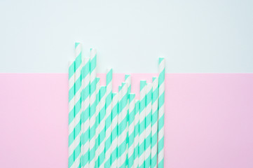 pile of paper striped white and green drinking straws for party on white and pink background. space for text