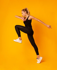 Fototapeta na wymiar Young Lady Jumping During Workout On Yellow Background, Side View