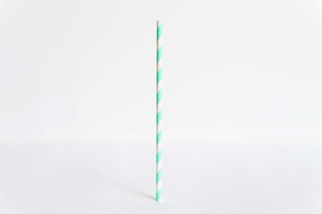 one paper striped white and green party drinking straw stands upright on a white background