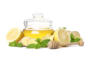 glass jar full of honey and dipper, ginger, lemon and mint isolated on a white background