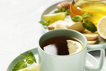 cup of hot tea with ginger, lemon and mint isolated on a white background