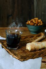 Hot coffee black with roll sweet bread on wood tray.