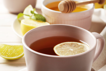 cup of hot tea with ginger, lemon and mint on a white wooden background